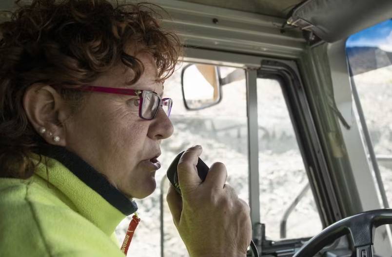 Cristina Carro speaks on an intercom while driving the quarry truck