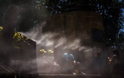 Personas se refrescan con agua nebulizada en el Zoológico de Madrid